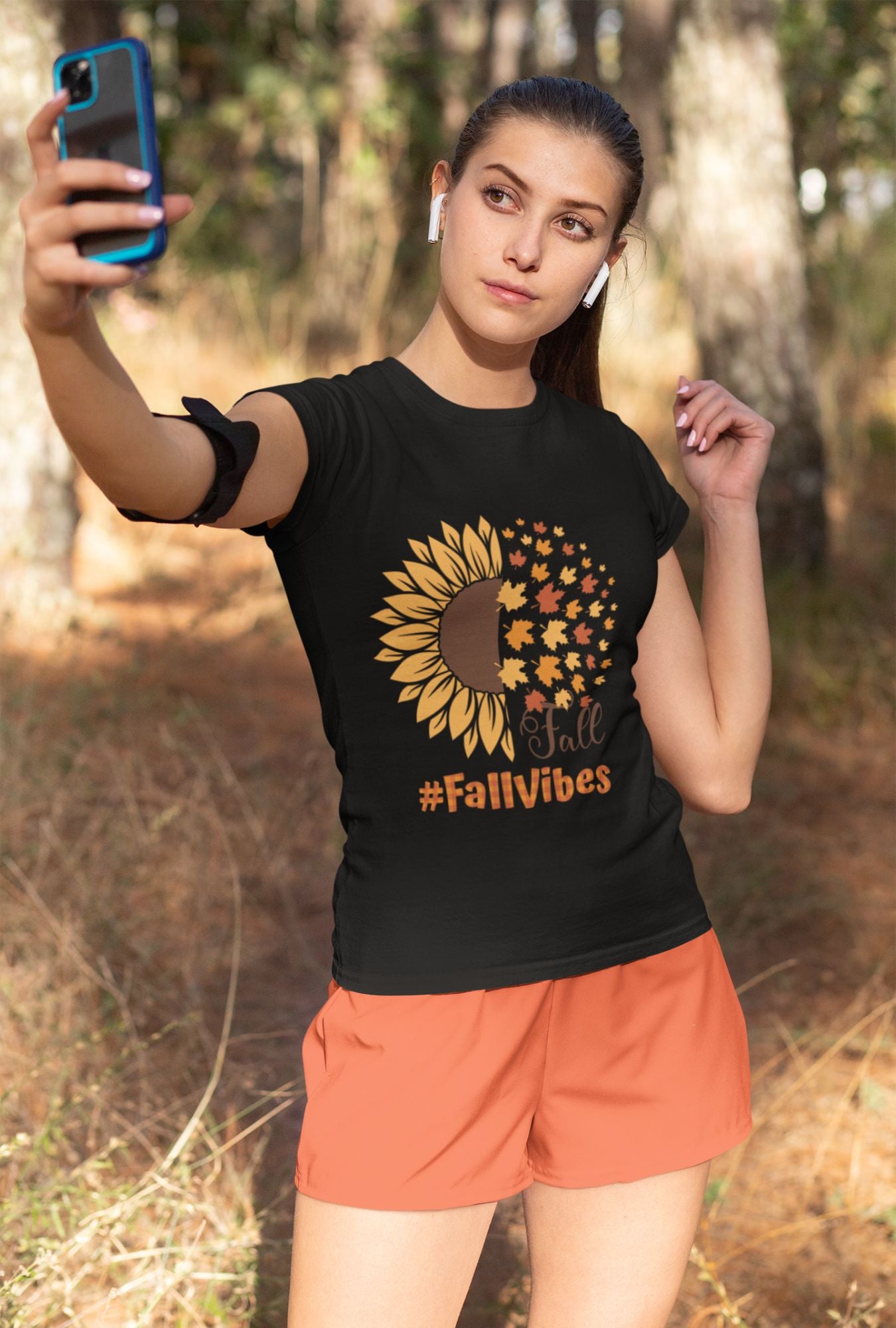 A woman wearing a RedBerry Cuddle 'Fall Vibes' Women's T-Shirt, made of 100% cotton. The black shirt features a sunflower graphic transitioning into autumn leaves with the words 'Fall' and '#FallVibes' in warm, autumnal colors.